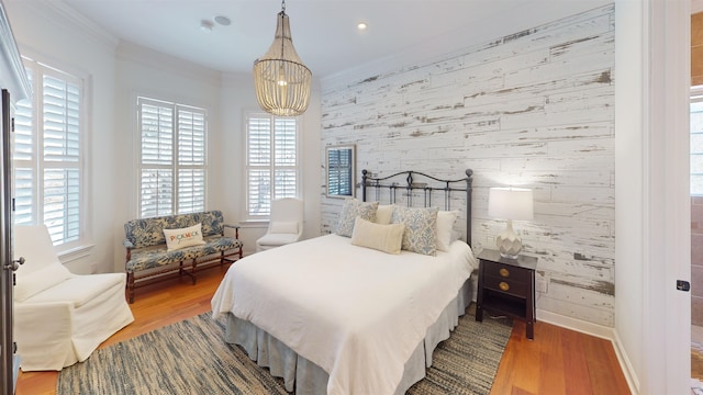 bedroom with crown molding, an accent wall, multiple windows, and wallpapered walls