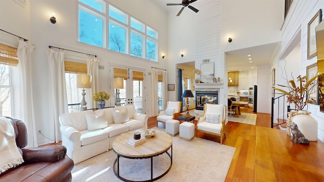 living room with ceiling fan, french doors, light wood-type flooring, and a multi sided fireplace