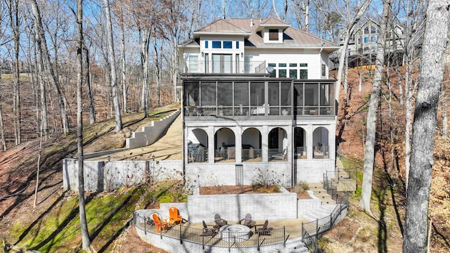 back of house with metal roof, an outdoor fire pit, a standing seam roof, and a sunroom