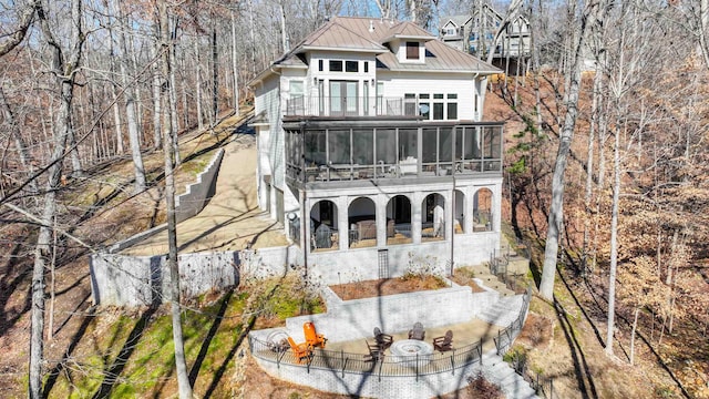 rear view of house featuring a sunroom, metal roof, a balcony, and a standing seam roof