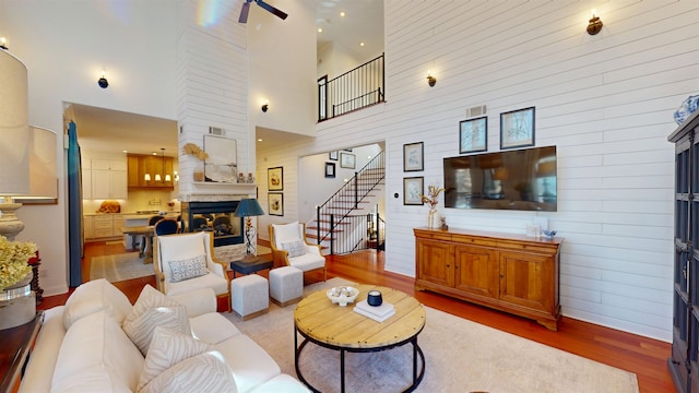 living area with wood walls, wood finished floors, visible vents, a multi sided fireplace, and stairs