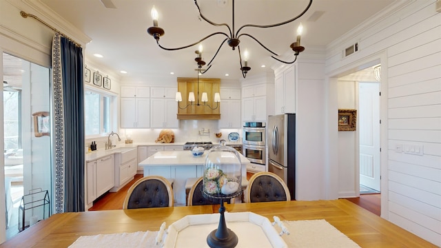 kitchen with decorative light fixtures, stainless steel appliances, light countertops, white cabinets, and a chandelier