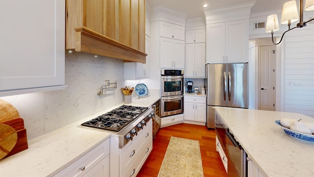 kitchen featuring white cabinetry, stainless steel appliances, light stone counters, and decorative light fixtures