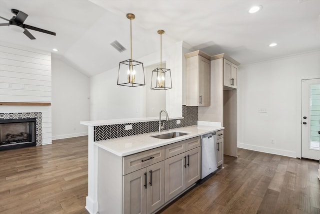 kitchen featuring dark wood-style flooring, decorative light fixtures, light countertops, stainless steel dishwasher, and a sink