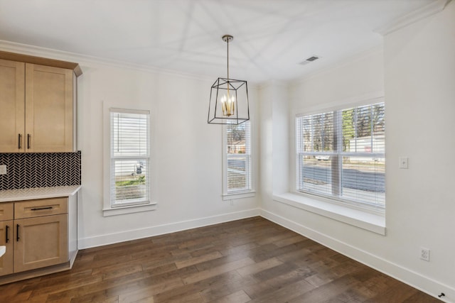 unfurnished dining area with baseboards, visible vents, dark wood finished floors, and crown molding