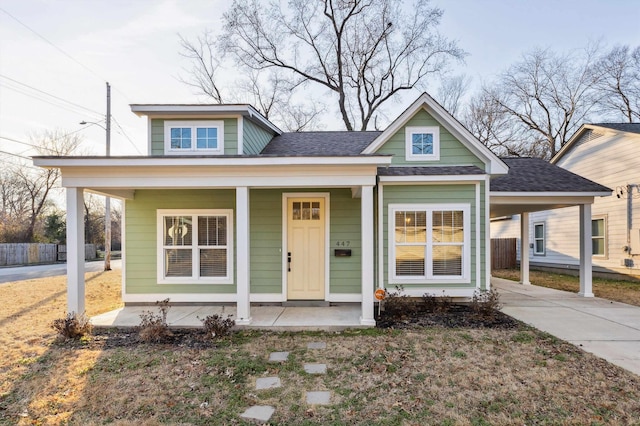 bungalow featuring covered porch, an attached carport, concrete driveway, and roof with shingles