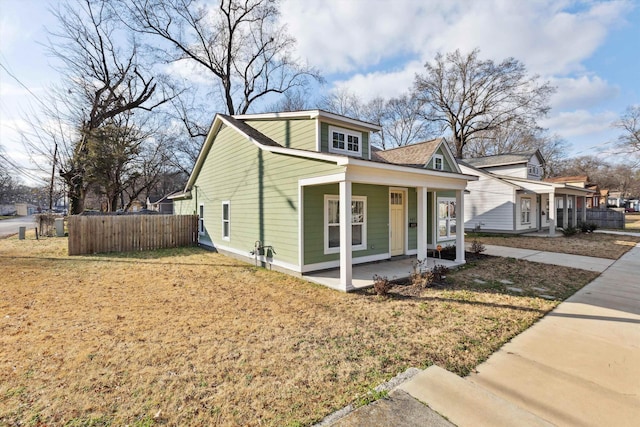 view of front of property with covered porch, a front lawn, and fence