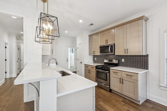 kitchen featuring appliances with stainless steel finishes, decorative light fixtures, a peninsula, light countertops, and a sink