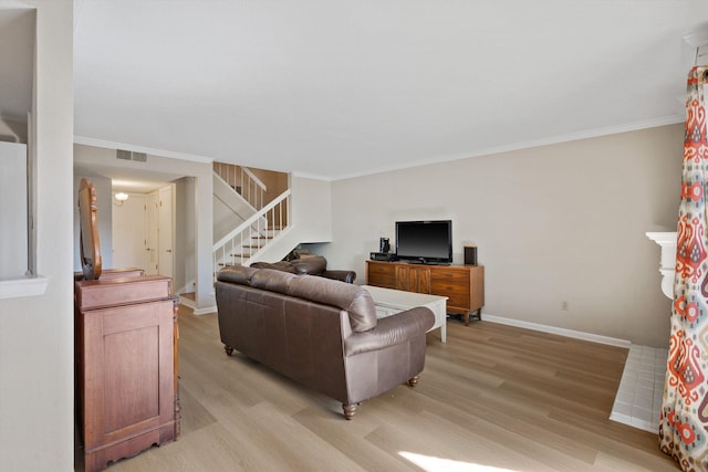 living room featuring baseboards, ornamental molding, stairway, and light wood-style floors