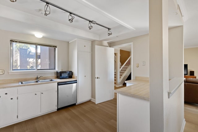 kitchen featuring a sink, light countertops, light wood-type flooring, black microwave, and stainless steel dishwasher