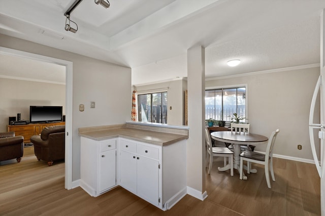 kitchen featuring light countertops, wood finished floors, white cabinetry, and baseboards