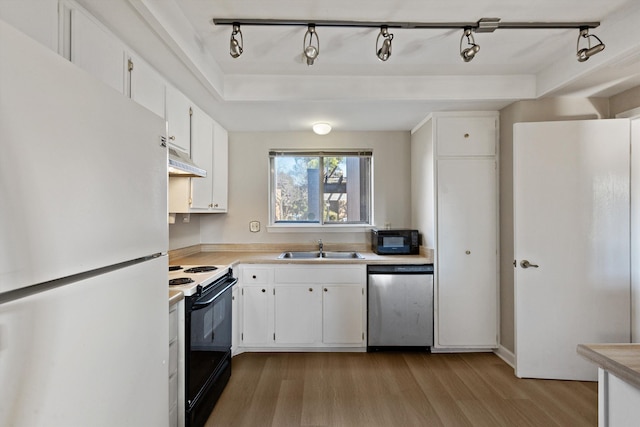 kitchen featuring under cabinet range hood, electric range, stainless steel dishwasher, freestanding refrigerator, and light wood finished floors