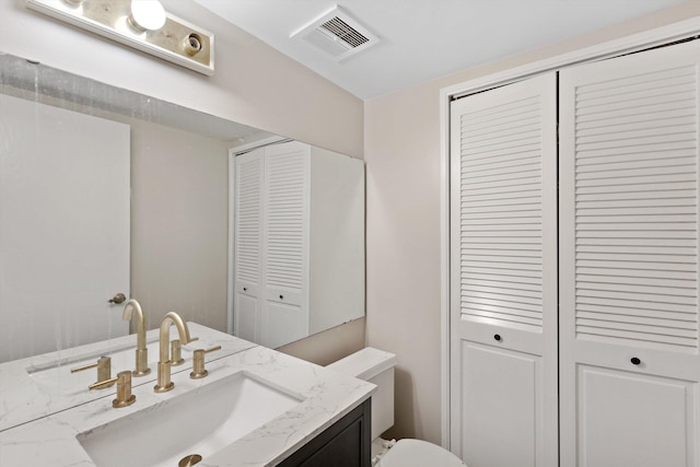 bathroom featuring a closet, visible vents, vanity, and toilet