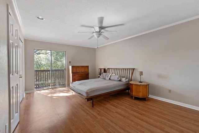 bedroom with ornamental molding, a textured ceiling, wood finished floors, access to outside, and baseboards