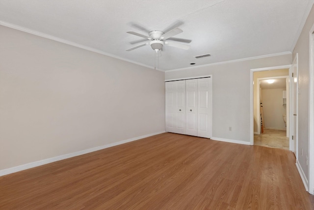 unfurnished bedroom with a closet, visible vents, ornamental molding, light wood-type flooring, and baseboards