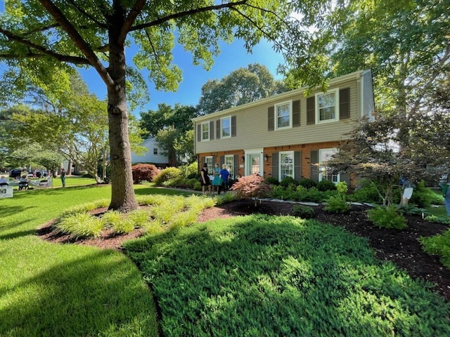 colonial inspired home featuring a front lawn and brick siding