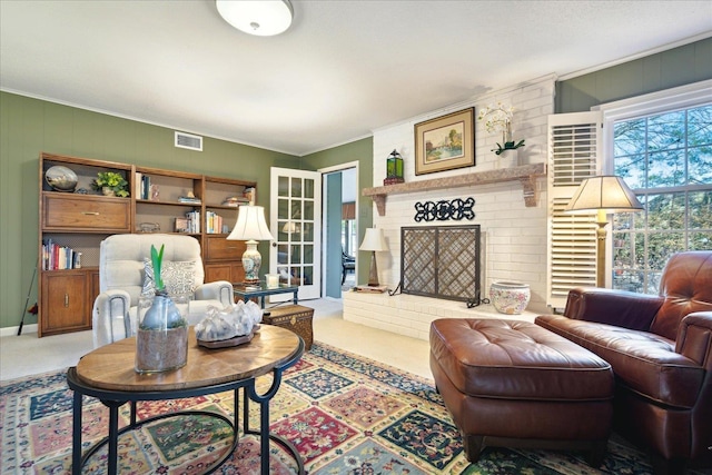 living area with a brick fireplace, carpet, visible vents, and crown molding