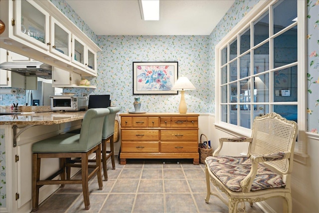 home office with light tile patterned floors, a toaster, and wallpapered walls