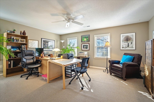 office area featuring light carpet, baseboards, visible vents, ceiling fan, and a textured ceiling