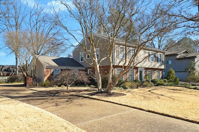 colonial home featuring driveway and brick siding