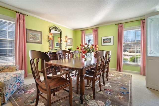 carpeted dining area featuring baseboards, a textured ceiling, and ornamental molding