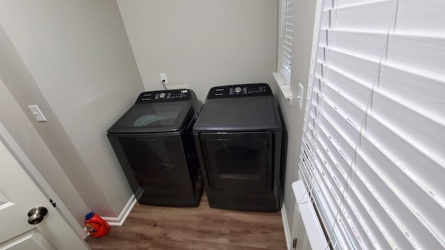 washroom featuring laundry area, washer and clothes dryer, light wood-style flooring, and baseboards