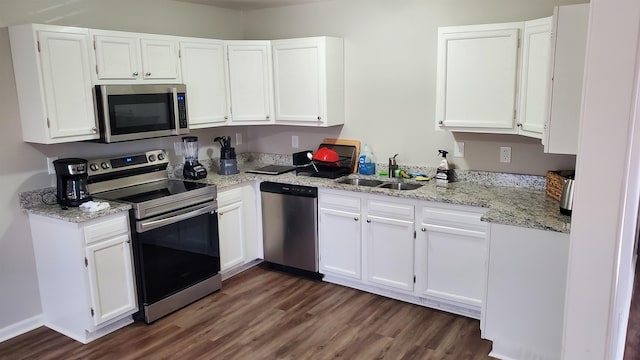 kitchen featuring dark wood-style floors, appliances with stainless steel finishes, light stone countertops, white cabinetry, and a sink