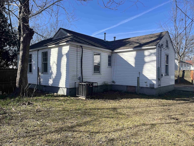 view of side of home with fence, central AC, and a yard