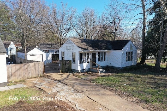 view of front of property featuring a front yard, fence, a garage, an outdoor structure, and driveway