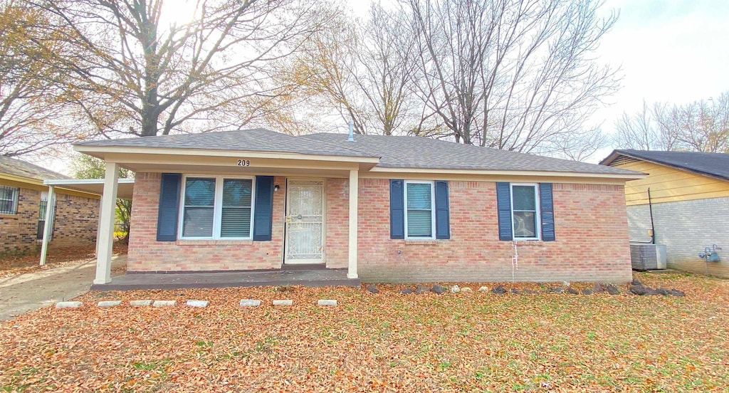 view of front of home featuring brick siding, a porch, cooling unit, and a shingled roof