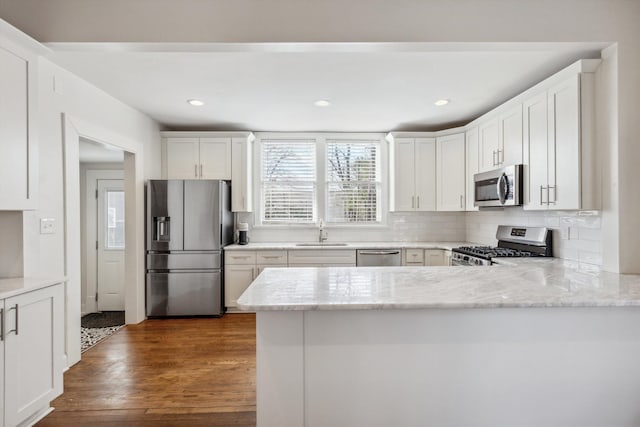 kitchen with stainless steel appliances, dark wood-type flooring, a sink, and white cabinets