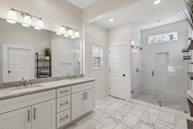 bathroom with double vanity, marble finish floor, a shower stall, and a sink