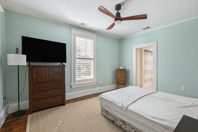 bedroom with dark wood-style floors, visible vents, crown molding, and baseboards