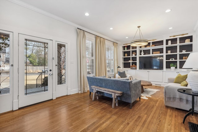 living area featuring ornamental molding, a wealth of natural light, and wood finished floors