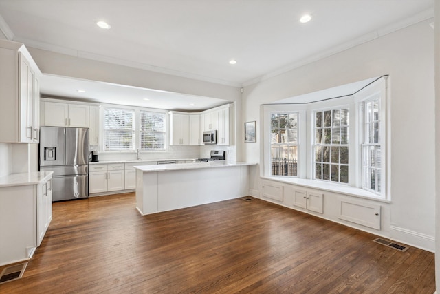 kitchen featuring stainless steel appliances, light countertops, visible vents, white cabinetry, and a peninsula