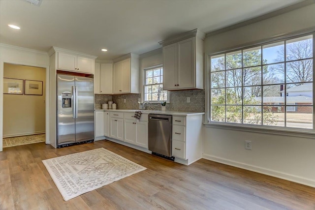 kitchen with appliances with stainless steel finishes, light countertops, crown molding, and white cabinetry