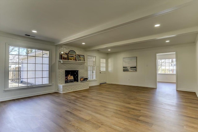 unfurnished living room with baseboards, visible vents, beamed ceiling, wood finished floors, and a fireplace