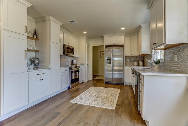 kitchen with stainless steel appliances, visible vents, white cabinets, light countertops, and open shelves