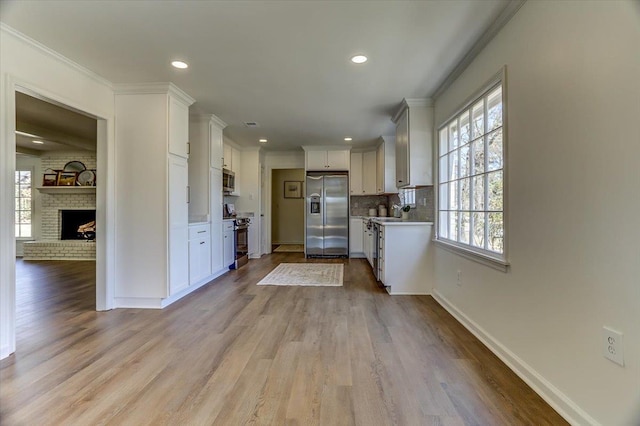 kitchen featuring stainless steel appliances, white cabinets, light countertops, and crown molding