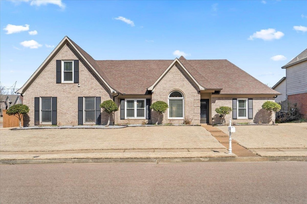 view of front of home featuring a shingled roof and brick siding