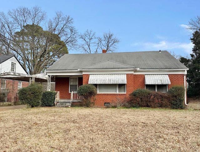 view of front of home with a shingled roof, a front yard, and brick siding