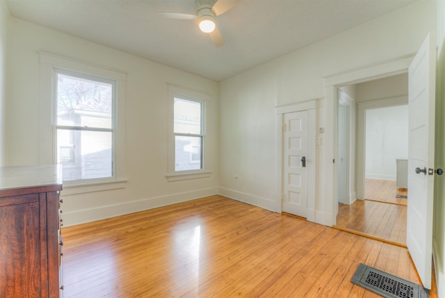 unfurnished room featuring light wood-style floors, baseboards, visible vents, and a ceiling fan