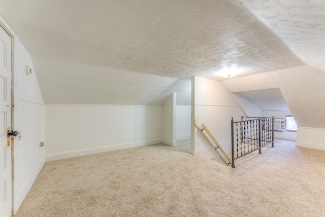 bonus room featuring light colored carpet, vaulted ceiling, and a textured ceiling