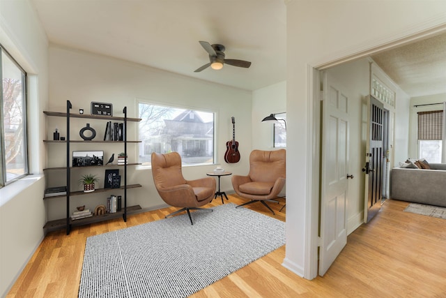 living area with light wood-type flooring and ceiling fan