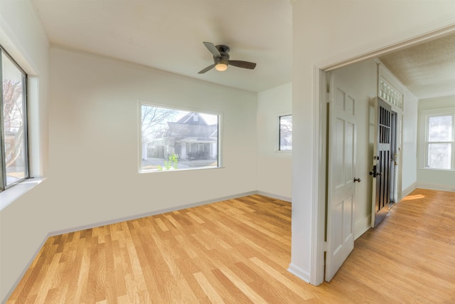 spare room with ceiling fan, light wood-style flooring, and baseboards