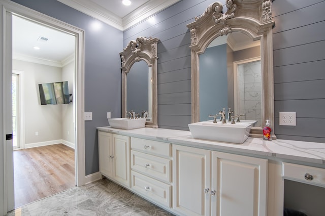 bathroom with double vanity, ornamental molding, a sink, and baseboards