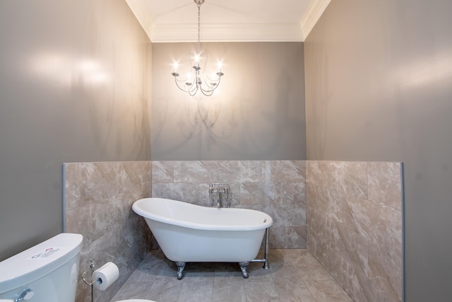 bathroom with toilet, an inviting chandelier, crown molding, a freestanding bath, and tile walls