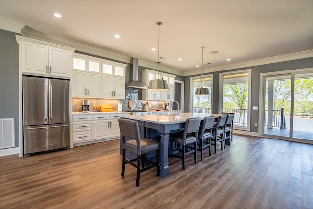 kitchen featuring wall chimney exhaust hood, visible vents, appliances with stainless steel finishes, and white cabinets