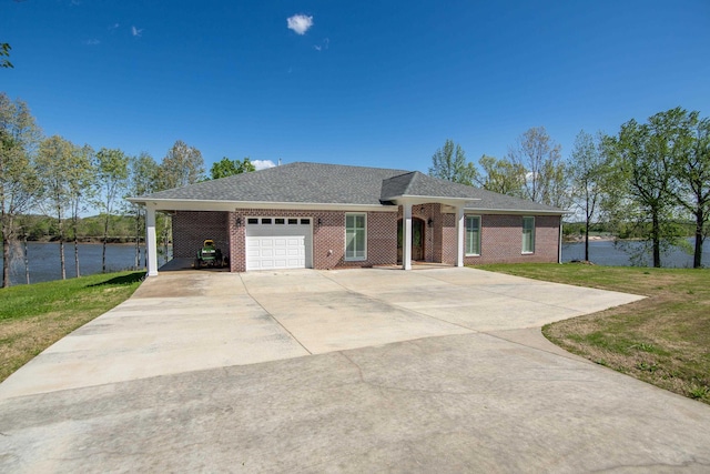 ranch-style home featuring brick siding, a water view, an attached garage, driveway, and a front lawn