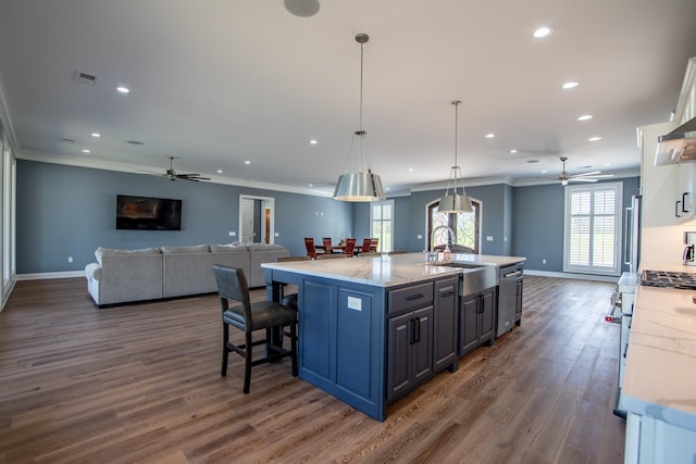 kitchen featuring high end stainless steel range oven, open floor plan, white cabinetry, a sink, and light stone countertops